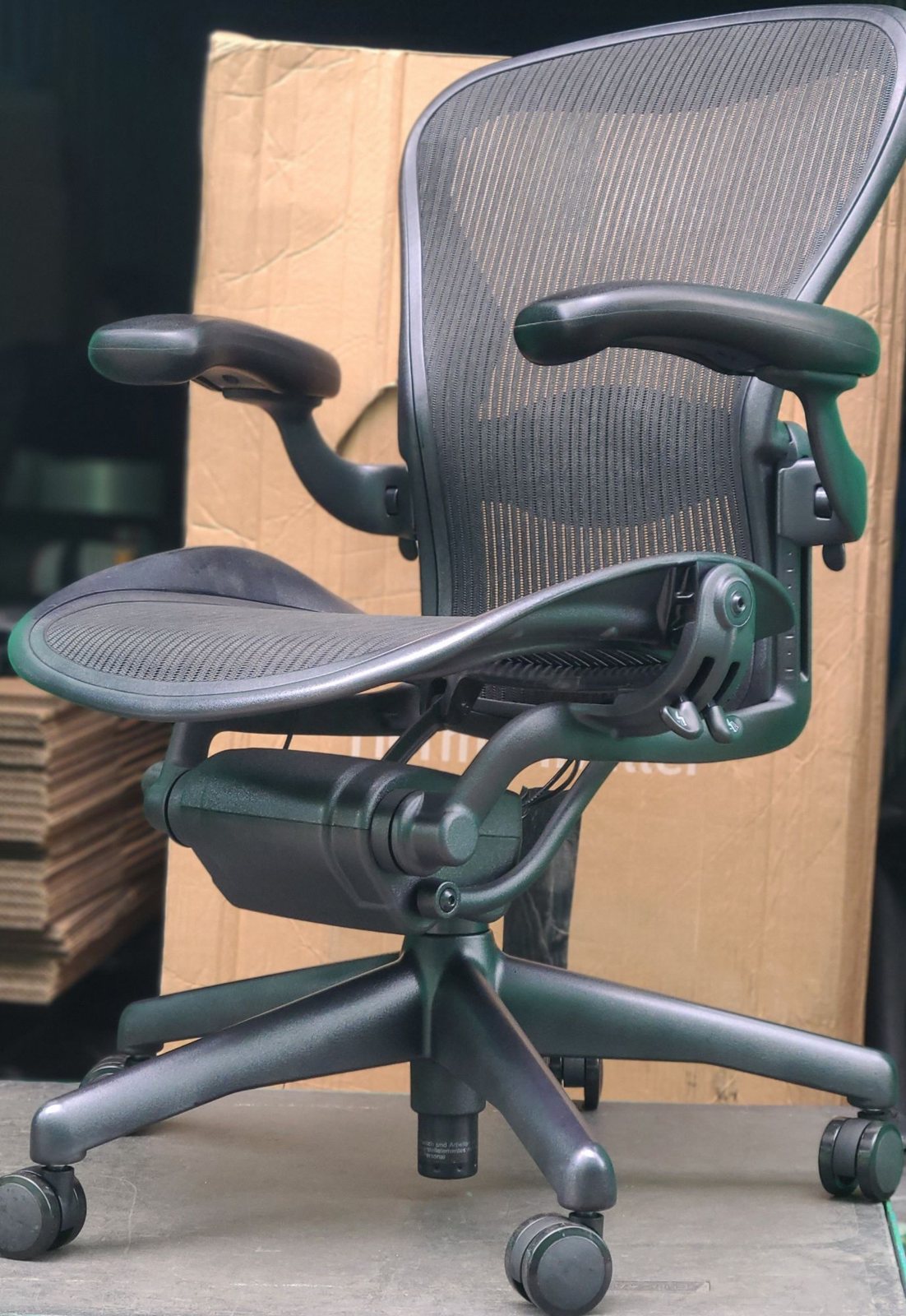 Assembled Herman Miller Aeron Classic chair in graphite, standing in front of its box